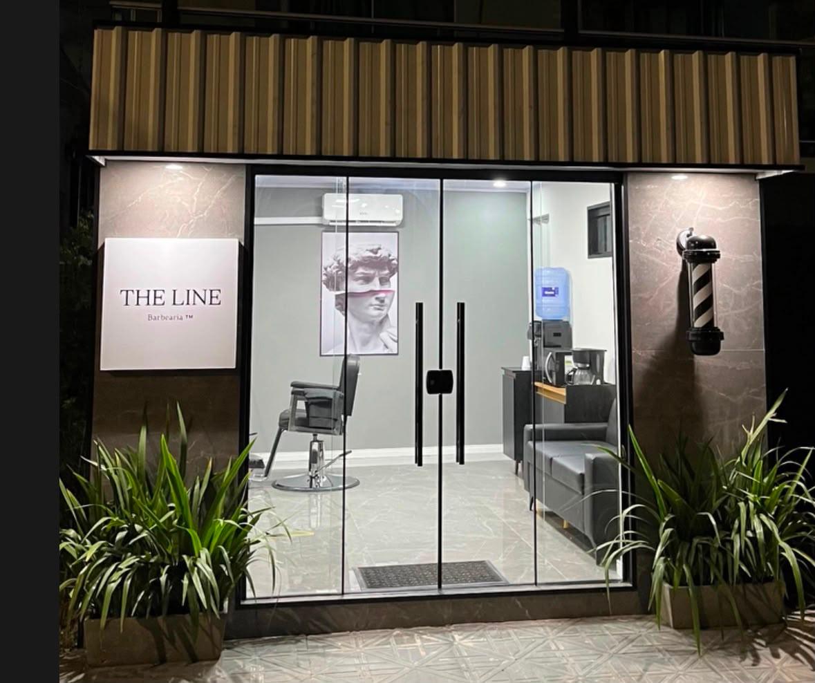 Fachada da The Line Barbearia à noite, em Itajaí